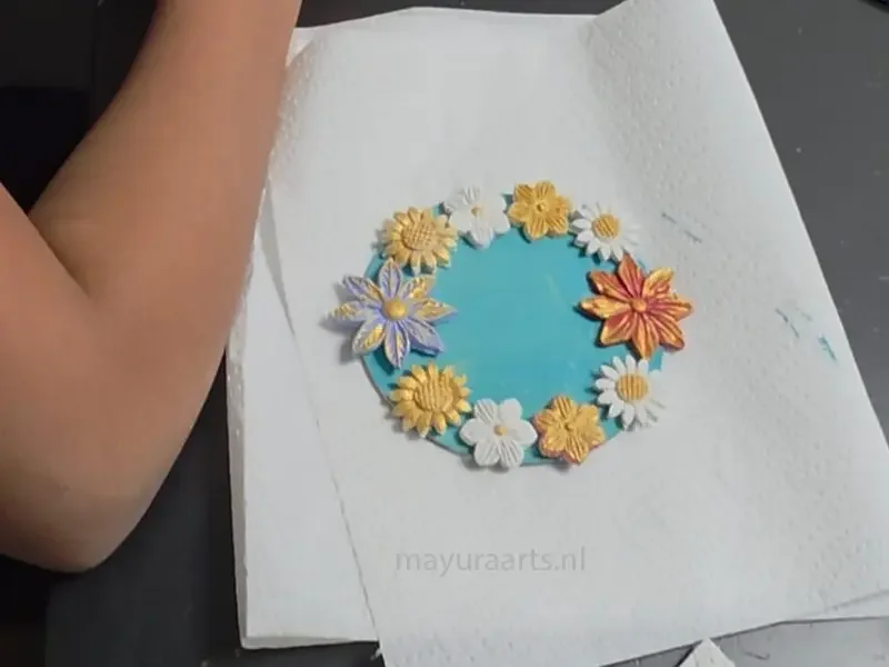 A finished clay craft featuring a circle of colorful sunflowers and daisies.