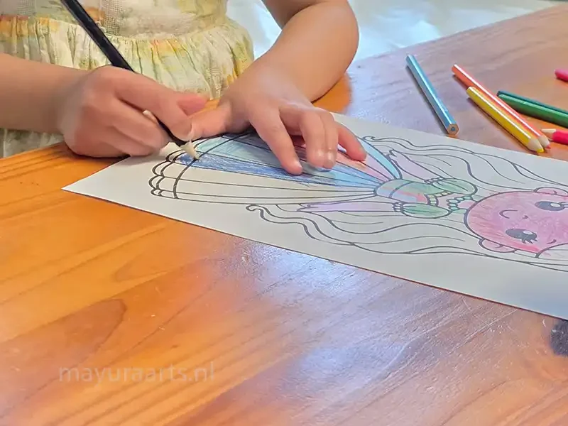 Close-up of a student coloring a princess drawing with a blue pencil.